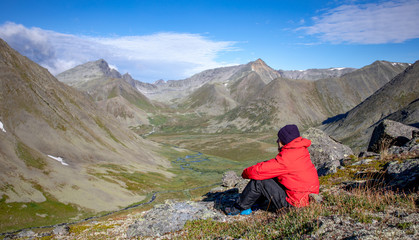 Fototapeta premium A man admires the mountains from a height. Summer sunny day in nature with a beautiful mountain landscape.