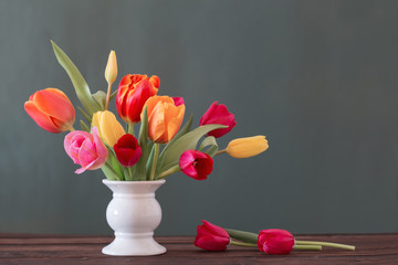 beautiful tulips in vase on green background