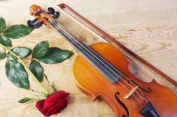 Fototapeta premium Violin and red rose on a wooden table