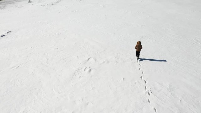 A man is walking along a snow field. Loneliness. View from above