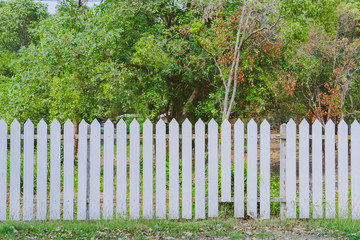 Old white wooden fence with a broken board at the roadside area
