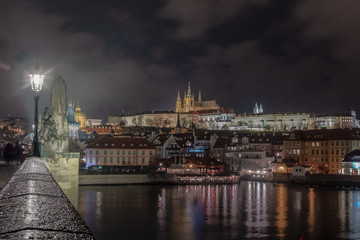 night image of Prague castle from Charles bridge with river in the foreground