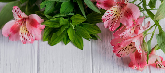 Background for text banner on a white wooden background with pink flowers. Blank, frame for text. Greeting card design with flowers. Aalstroemeria on wooden background. View from above