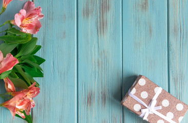 Frame for greeting text with natural flowers, butterflies, gift. Background for a banner of blue color with flowers of Alstroemeria. Flat lay, top view.