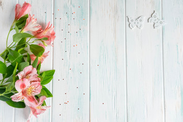 Background for text banner on a white wooden background with pink flowers and butterflies. Blank, frame for text. Greeting card design with flowers. Aalstroemeria on wooden background. View from above