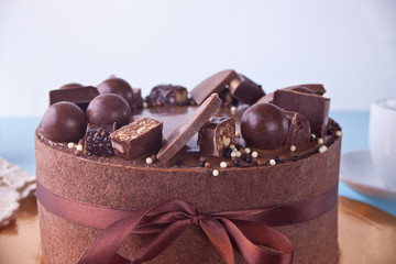 Chocolate cake with candy and ribbon on a blue table