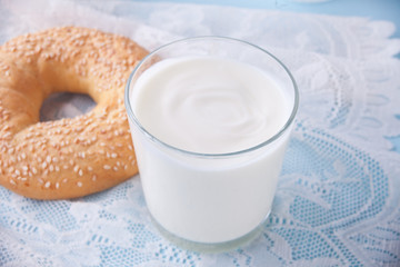 Yogurt in glass and fresh bagel on a table with white napkin.