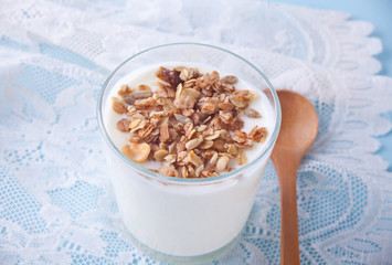 Granola with yogurt in glass with wooden spoon on a table.