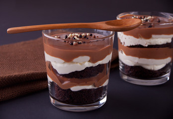 Chocolate dessert in glass jars on a table with wooden spoon