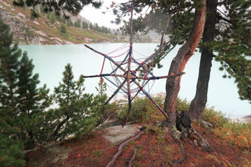 Knitted tibetan mandala from threads and yarn. Mountain lake on the background. Hand crafted and...