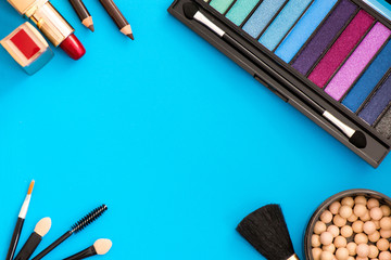 Top, up view of professional cosmetics, makeup background. Brushes, eye shadows, eyebrow pencils, powder, bronzing balls, mascara, red lipstick. Tools isolated on blue. Concept of get ready for party