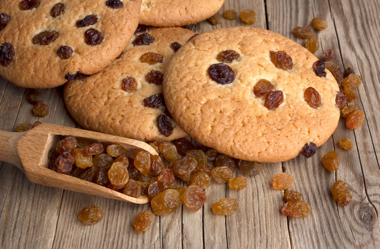 Oatmeal cookies with raisins,  on a dark wooden background with a wooden spoon