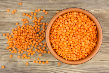 Red lentils in plate on wooden background