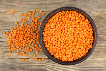 Red lentils in plate on wooden background