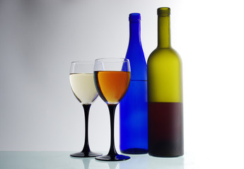 Two glasses of wine and two bottles on a light