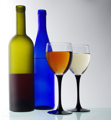 Two glasses of wine and two bottles on a light
