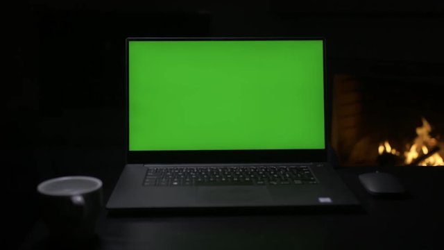 Laptop green screen with fireplace at the background. Slow motorized slide camera movement.