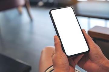 Mockup image of woman's hands holding black mobile phone with blank white screen in cafe