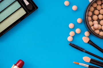 Top, up view of professional cosmetics, makeup background. Brushes, eye shadows, eyebrow pencils, powder, bronzing balls, mascara, red lipstick. Tools isolated on blue. Concept of get ready for party
