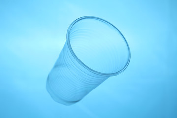 Plastic cup in blue water, plastic pollution of oceans.