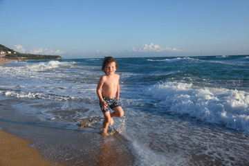Fototapeta na wymiar Child running and play at beach. Little boy play by the sea on summer vacation