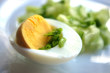 Half an egg with green onions, chopped egg, vegetable salad. Macro yellow yolk, white egg white, chopped onion. Useful breakfast, menu for restaurant, recipe book. Food on a transparent plate.