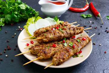 Lula kebab is a traditional Arabic dish. Meat shashlik on wooden skewers on black background.
