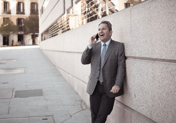 Portrait of handsome middle aged smart businessman walking in the city talking on mobile phone