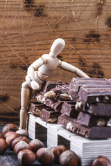 Czekolada ukladana na palecie przez drewnianego ludzika, lalke, magazyn czekolady. - obrazy, fototapety, plakaty