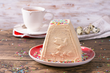 Traditional Russian Easter cottage cheese dessert, Orthodox Paskha, with boiled condensed milk on a wooden table