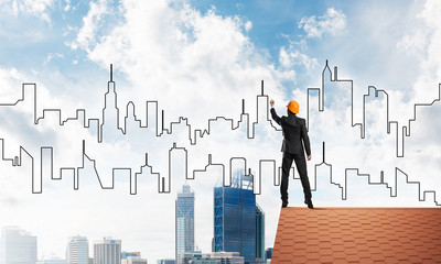 Man architect draw silhouette of modern city on blue sky. Mixed media