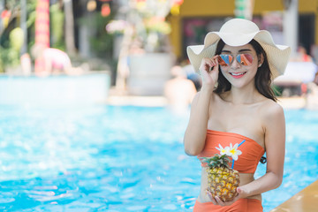 Beautiful Asain women with bikini enjoy summer vacation in the swimming pool.