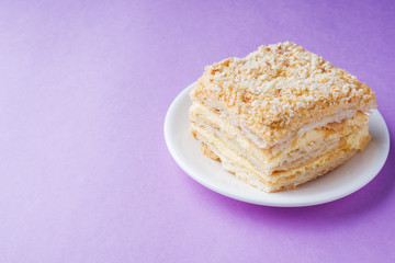 Puff cake with cream Napoleon Millefeuille vanilla slice color on purple background.