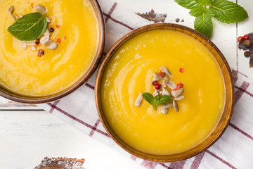 Pumpkin soup mashed with spices in wooden bowls on light boards.