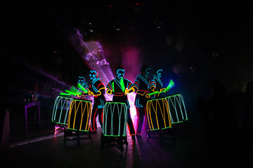 laser show performance, dancers in suits with LED lamp