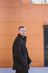 A man with a beard in a warm winter brown jacket poses for advertising of men's clothing in the winter. Advertising of men's clothing