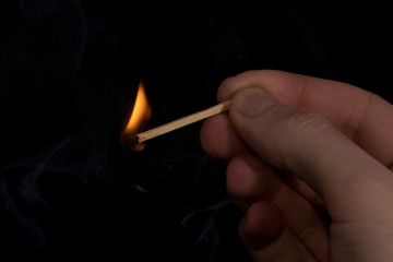 lit a match in his hand on a black background