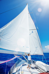 Obraz premium Little boy on board of sailing yacht on summer cruise. Travel adventure, yachting with child on family vacation.