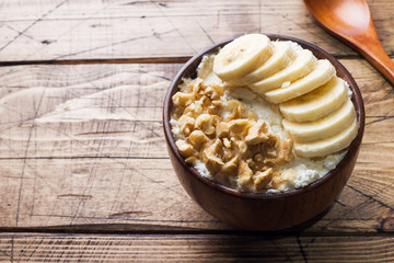 Healthy breakfast. Cottage cheese with banana and walnuts on wooden background.