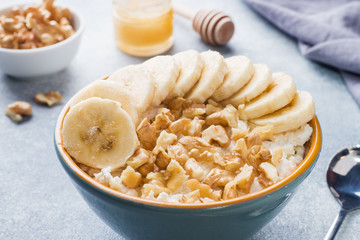 Healthy breakfast. Cottage cheese with banana and walnuts on grey background.