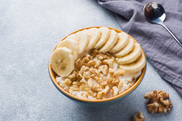 Healthy breakfast. Cottage cheese with banana and walnuts on grey background.