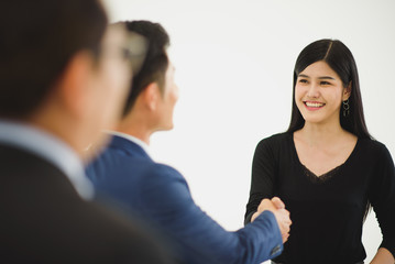 Closed up of business people shaking hands which standing in front of white background at the working place.