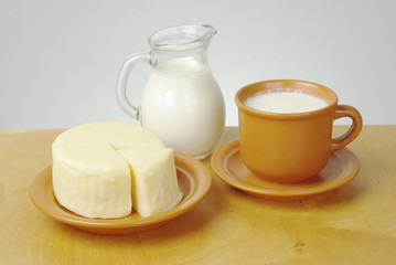  A jug of milk, a piece of cheese on a saucer. Isolated on white