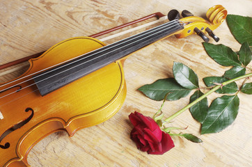 Fototapeta premium Violin and red rose on a wooden table. Copy space