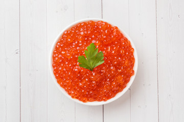red salmon caviar in a plate on a white table.