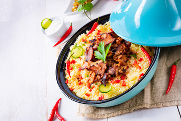 Tajin with couscous, vegetables and meat on white background