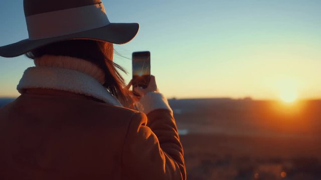 Young girl doing a photo of sunset