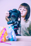 Closeup of a happy little cute child girl photographer with a camera. Selective focus on eye.