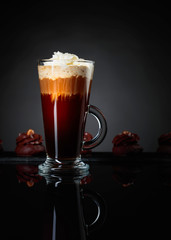 Layered coffee cocktail with chocolate dessert on a black reflective background.