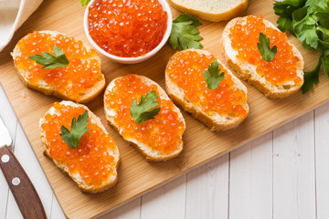 Sandwiches with red salmon caviar on a wooden Board. White table top.
